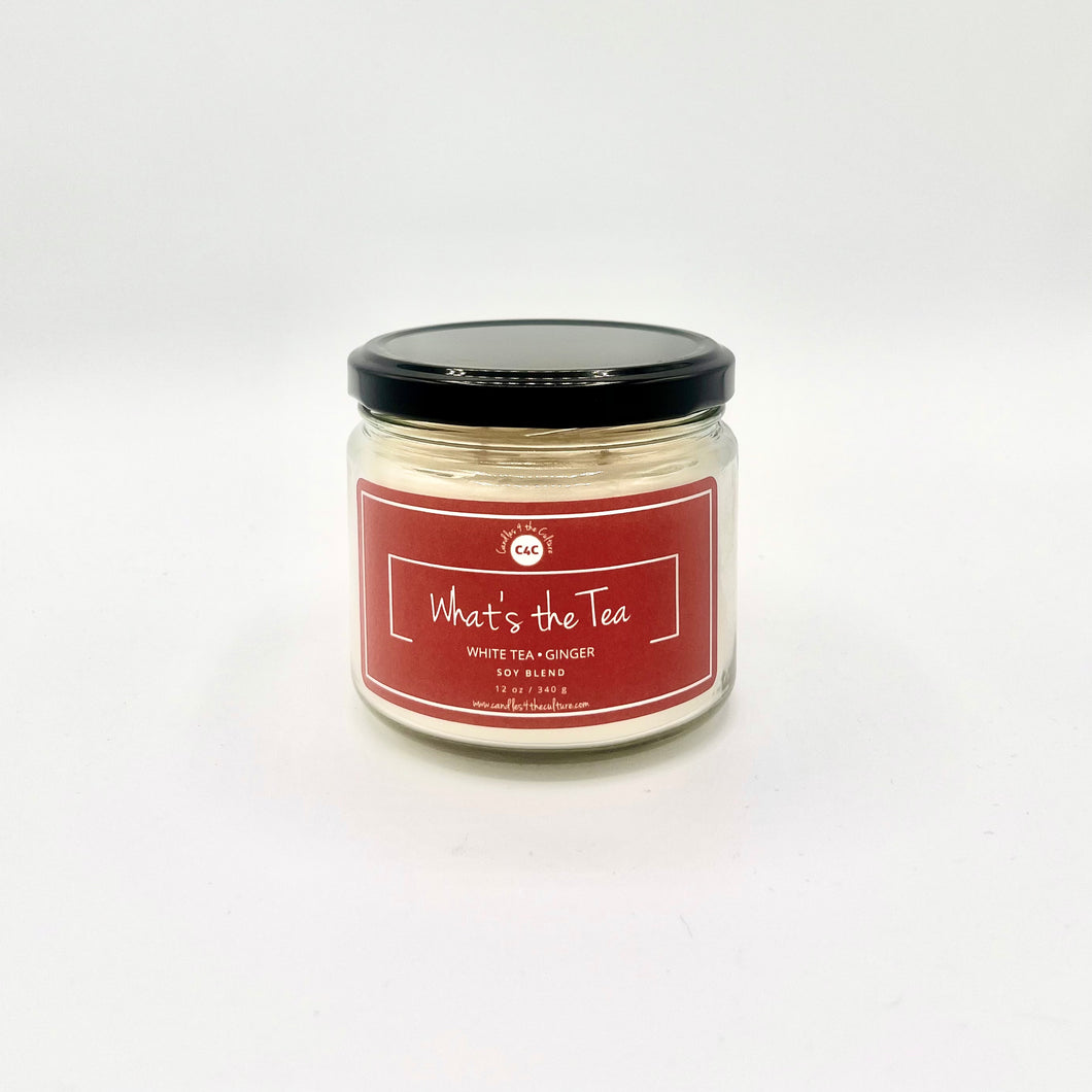 12 oz glass jar candle with cotton wicks and soy blend wax, designed to enhance self-care and evoke nostalgia. Orange label reads 'What's the Tea'. Fragrance invites a spa-like experience with invigorating white tea and ginger scents, promoting relaxation and rejuvenation.