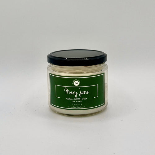 12 oz glass jar candle with cotton wicks and soy blend wax, designed to enhance self-care and celebrate culture. Green label reads 'Mary Jane'. Fragrance is both floral and earthy, capturing the essence of the cannabis flower.