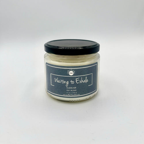 12 oz glass jar candle with cotton wicks and soy blend wax, crafted to enhance self-care and evoke nostalgia. Bluish gray label reads 'Waiting to Exhale'. Fragrance is designed to capture the true essence of clean air.