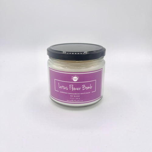 12 oz glass jar candle with cotton wicks and soy blend wax, crafted to enhance self-care and celebrate culture. Fuchsia label reads 'Lotus Flower Bomb'. Fragrance captures the essence of a gardenia flower in full bloom.