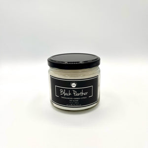 12 oz glass jar candle with cotton wicks and non-toxic fragrance. Soy blend wax scented with a captivating blend of complex, woody notes infused with five essential oils. Black label reads 'Black Panther.' Enhance self-care with pride and nostalgia.
