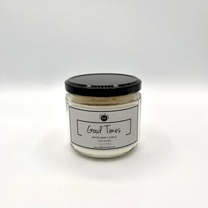 12 oz glass jar candle with cotton wicks and soy blend wax, featuring a non-toxic fragrance. Designed to evoke feelings of pride, self-worth, and nostalgia in Black women. Fragrance is a blend of white sage and citrus to relax and brighten your mood. Gray label reads 'Good Times'.